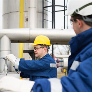 Men with hardhats and protective goggles in front of an industrial setting