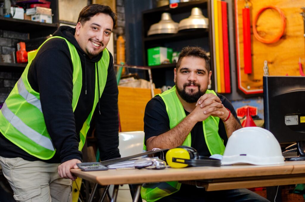 Two smiling workers dressed in hivis with an industrial background setting